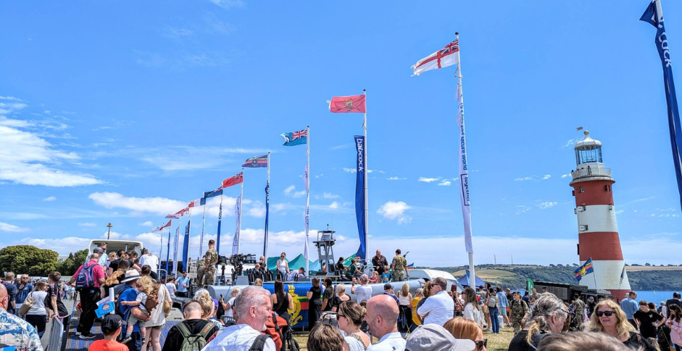 Crowds on plymouth Hoe for Armed Forces Day with Flag Poles and Smeaton's Tower on the right 